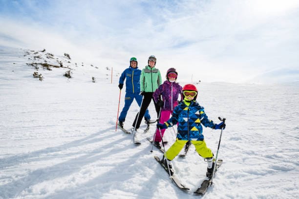 Familia iniciándose en el esquí realizando frenado en cuña y mejorando su nivel de esquí.