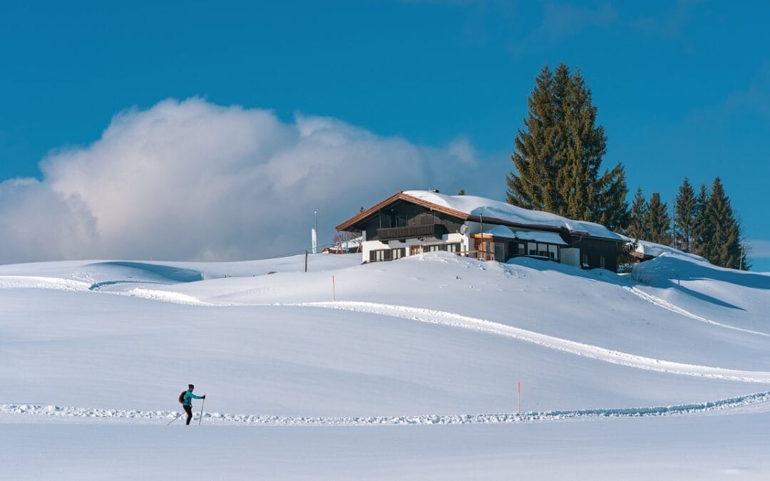 Paisaje nevado junto a un refugio por el que transcurren las pistas de esquí. Se puede apreciar a un esquiador disfrutando de la nieve.